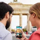 Paar mit neuer App "About Berlin" vorm Brandenburger Tor